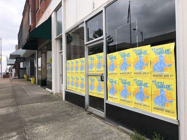 Walmart Yodel Boy concert posters wheatpasted across storefront windows in downtown Harrisburg, Illinois